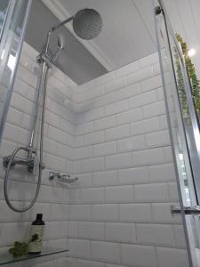 a shower in a bathroom with white tiles at Tiny Home on Broadway in Gqeberha