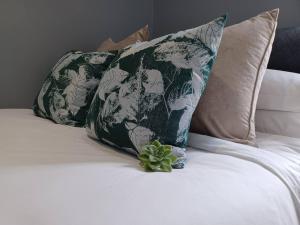a green and white pillow and a plant on a bed at Tiny Home on Broadway in Gqeberha