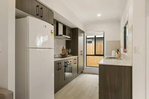a kitchen with a white refrigerator and a sink at Dual key 5BR Family home with stunning interior in Browns Plains