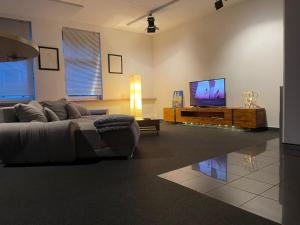 sala de estar con sofá y TV de pantalla plana en 140 qm großes Loft mit 2 Schlafzimmern im Fabrikstil, en Gross-Umstadt