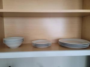 three plates and bowls are sitting on a shelf at Private Vacational Cozy Suite in Kissimmee