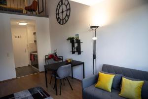 uma sala de estar com um sofá, uma mesa e um relógio em Loftcharakter auf 2 Etagen - Zentral in Essen! em Essen