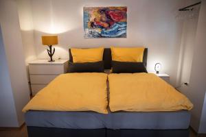 a bedroom with a bed with yellow sheets and a painting at Loftcharakter auf 2 Etagen - Zentral in Essen! in Essen