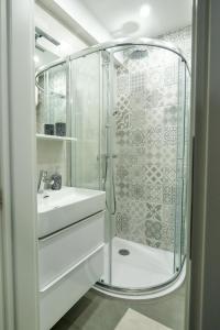 a white bathroom with a shower and a sink at Apartman Cesarac in Osijek