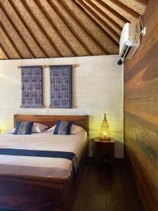a bedroom with a bed and a lamp on a table at Indigo Bungalows in Gili Trawangan