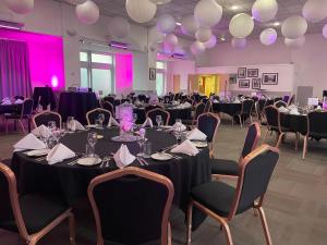 un salón de banquetes con mesas redondas y sillas con iluminación púrpura en Pendulum Hotel, en Mánchester