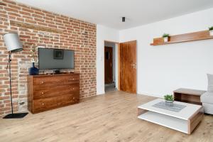 a living room with a tv and a brick wall at APARTAMENT PRZY RYNKU II in Chełmno