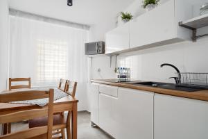 uma cozinha com armários brancos, uma mesa e um lavatório em APARTAMENT PRZY RYNKU II em Chełmno