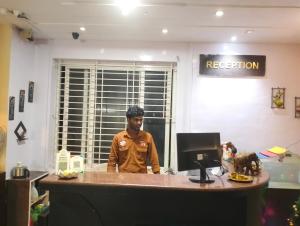 a man standing in front of a desk with a computer at Madurai Grands Inn in Madurai