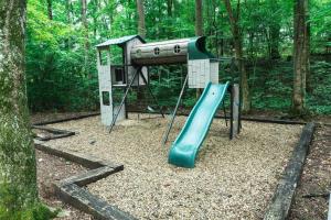 a playground with a slide in the woods at Tiny Home Cottage Near the Smokies #7 Tilly in Sevierville