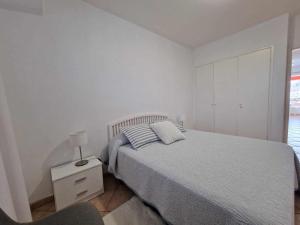- une chambre blanche avec un lit et une chaise dans l'établissement MarketHome Playa la Arena I, à Santiago del Teide