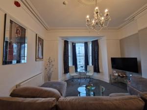 a living room with a couch and a chandelier at Montague House Apartments in Llandudno