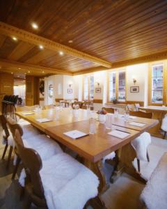 un grande tavolo in legno in una stanza con sedie di Hotel de Commune a Gstaad