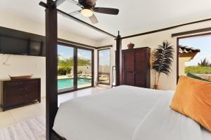 a bedroom with a bed with a ceiling fan at Arashi Palm Villa in Noord