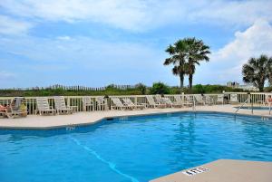 a swimming pool with lounge chairs and palm trees at 309A Sea Cabin in Isle of Palms