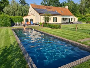 a swimming pool in the yard of a home with a house at Cottage de Vinck in Ieper
