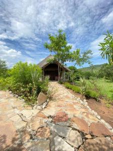 un chemin en pierre menant à une maison au toit de chaume dans l'établissement Eco Mara Tented Camp, à Ololaimutiek