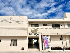 a white building with a nikka sign on it at Nuxká Hotel by Heaven in Telchac Puerto