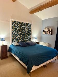 a bedroom with a blue bed with a painting on the wall at Le Pavillon Vert - B&B in Vedène