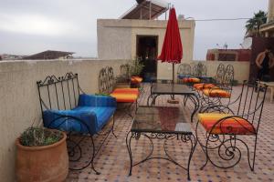 un patio con sillas, mesas y una sombrilla roja en Riad Andalousse en Meknès