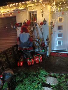 une femme assise sur un banc devant une maison aux lumières de Noël dans l'établissement Chez sarah, à Issenheim