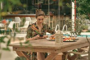 a woman sitting at a table with a plate of food at Georgia's Garden by Omilos Hotels in Amoudara Herakliou