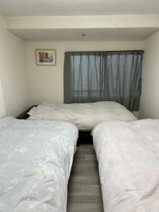 3 Betten in einem Zimmer mit Fenster in der Unterkunft 小樽民泊太田5号館 in Kita-hamachō