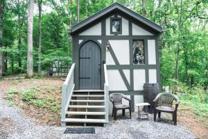 un pequeño cobertizo con 2 sillas y una puerta en Tiny Home Cottage Near the Smokies #8 Helga, en Sevierville