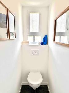 een witte badkamer met een toilet en 2 ramen bij Superbe 8 couchages 200m de la mer - terrasse/clim in Saint-Raphaël
