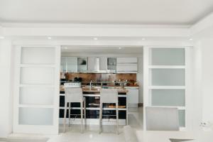 una cucina con armadietti bianchi e sgabelli da bar di Oceanfront 3 Bedrooms With Pool a Santo Domingo