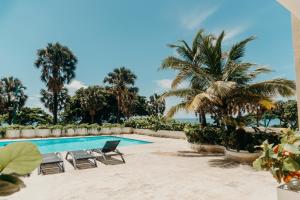 a swimming pool with chairs and palm trees at Oceanfront 3 Bedroom With Jacuzzi and Pool in Santo Domingo