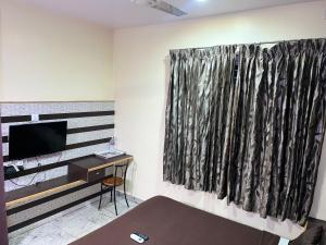 a living room with a television and a window at Madurai Grands Inn in Madurai
