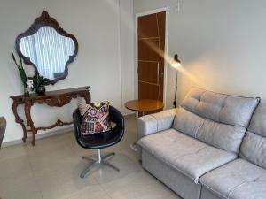 ein Wohnzimmer mit einem Sofa und einem Stuhl in der Unterkunft Apto Solar das Calêndulas - Temporada confortável em Floripa in Florianópolis
