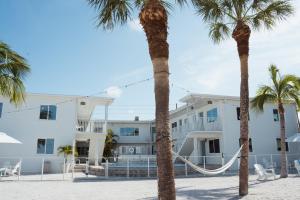 un edificio con palmeras delante en Molloy Gulf Motel & Cottages, en St Pete Beach