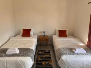 two twin beds in a room with a side table at White Rhino apartments & tours in Livingstone