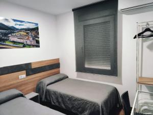 Habitación pequeña con cama y ventana en Hostal Rioja Condestable, en Logroño