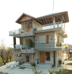 a large house with a balcony on top of it at Shepherds Of Dharamshala in Dharmsala