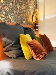 un grupo de almohadas sentado encima de una cama en Le Constantin - Ecrin chaleureux & confortable, centre-ville à 2 pas, en Provins