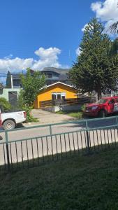 una calle con coches aparcados frente a una casa amarilla en Hostal Sur Y Magia, en Coyhaique