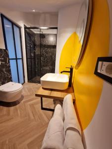 a bathroom with a white sink and a yellow wall at RaHouse - Self Check-in & Free Parking in Braşov