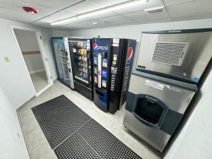 Motel 6 East Syracuse, NY - Airport في إيست سيراكيوز: غرفة مع آلة بيع وثلاجة للمشروبات