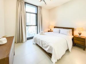 a white bedroom with a large bed and a window at Amazing Burj and Opera View Apartment 163BC-2 in Dubai