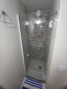 a shower in a bathroom with a blue and white rug at Apartamento 120 metros da praia in Guarapari