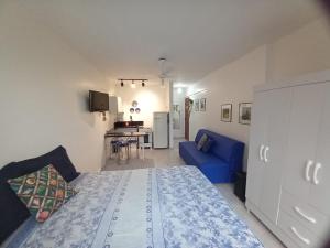 a bedroom with a bed and a blue couch at Apartamento 120 metros da praia in Guarapari