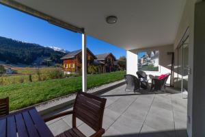 a patio with chairs and a table and a large window at Rietgarten in Wildhaus