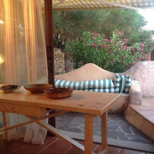 a wooden table and a couch on a patio at Sa Codina in Marina di Portisco