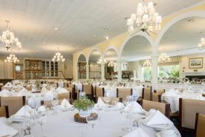 a dining room with white tables and chairs and chandeliers at Airlie in Warrenton