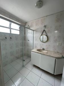 W łazience znajduje się prysznic, umywalka i lustro. w obiekcie Apartamento a 100m. da Praia de Pitangueiras w mieście Guarujá