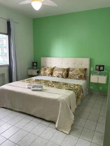 sypialnia z dużym łóżkiem i zieloną ścianą w obiekcie Apartamento a 100m. da Praia de Pitangueiras w mieście Guarujá