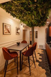 une salle à manger avec une table, des chaises et un arbre dans l'établissement L'improbable raffiné, élégant et chaleureux, 